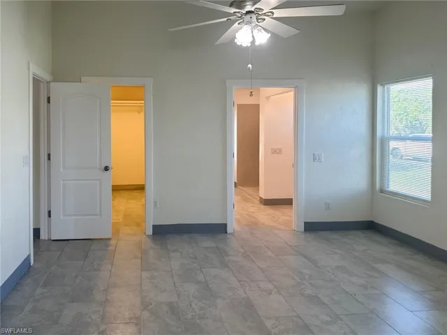 Unfurnished bedroom with a walk in closet and ceiling fan