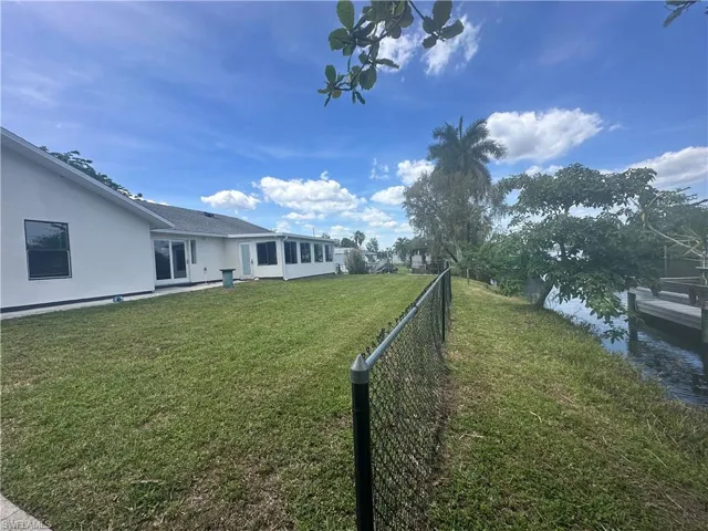 Waterfront property featuring a sunroom, expansive lawn, and a private dock