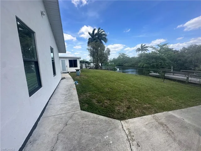 Waterfront property featuring a grassy yard, mature trees, and a private dock