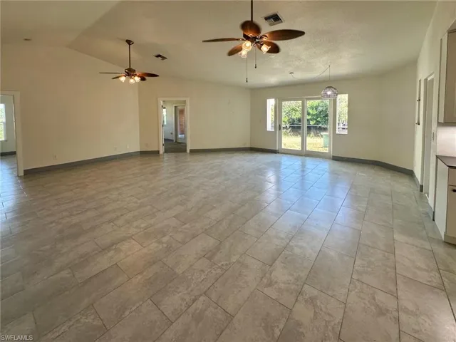 Unfurnished living room featuring a ceiling fan, vaulted ceiling, and healthy amount of natural light