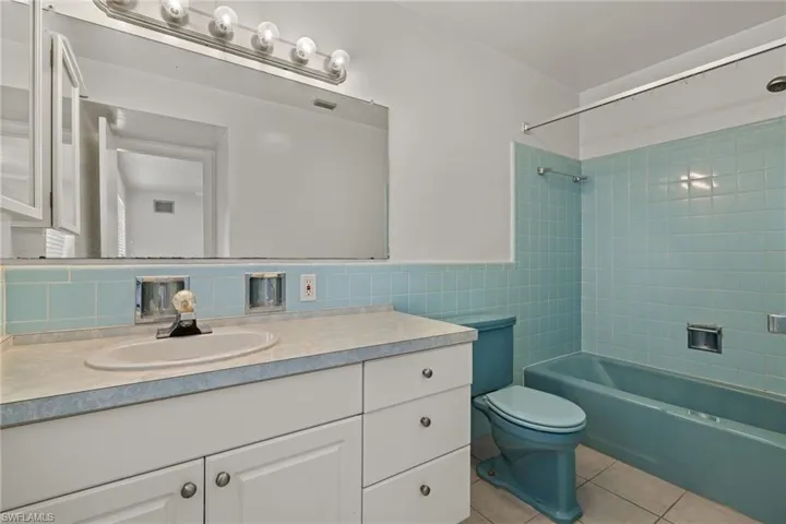 Full bathroom featuring toilet, tile patterned floors, tiled shower / bath, vanity, and decorative backsplash