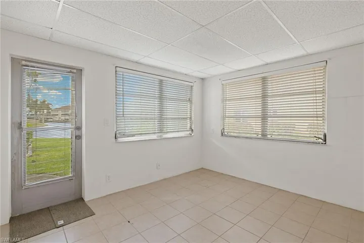Empty room with light tile patterned floors and a drop ceiling