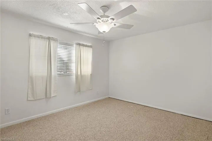 Spare room featuring a textured ceiling, carpet flooring, and ceiling fan