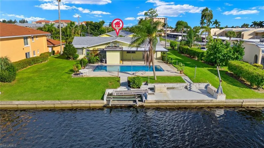 Rear view of house with a patio area, a lawn, a community pool, and a water view