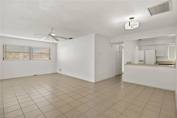 Unfurnished living room featuring a textured ceiling, light tile patterned flooring, and ceiling fan