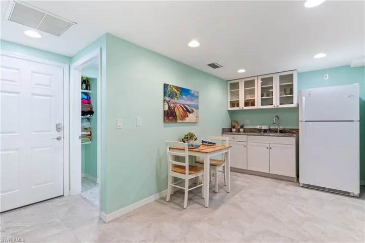Kitchen featuring white refrigerator, white cabinetry, and sink