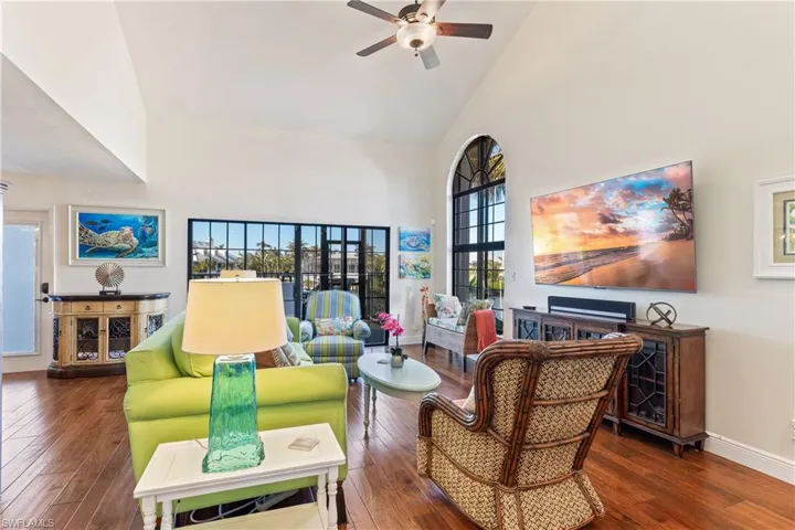 Living room featuring  hardwood floors, high vaulted ceiling, a wealth of natural light, and ceiling fan