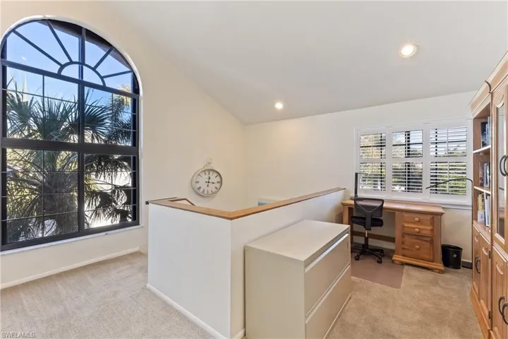 Carpeted home office with lofted ceiling