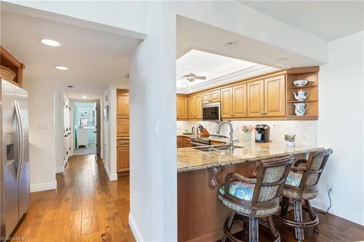 Kitchen with kitchen peninsula, appliances with stainless steel finishes, stone countertops, and sink