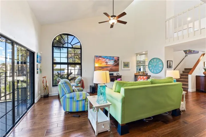 Living room featuring  hardwood flooring, high vaulted ceiling, and ceiling fan