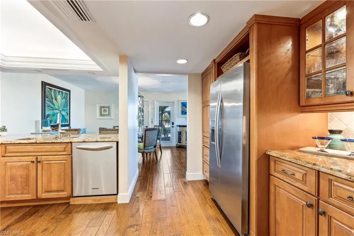 Kitchen featuring stone countertops, appliances with stainless steel finishes, decorative backsplash, sink, and  wood flooring