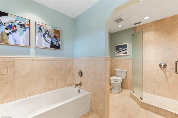 Bathroom with shower with separate bathtub, toilet, tile walls, and tile patterned floors
