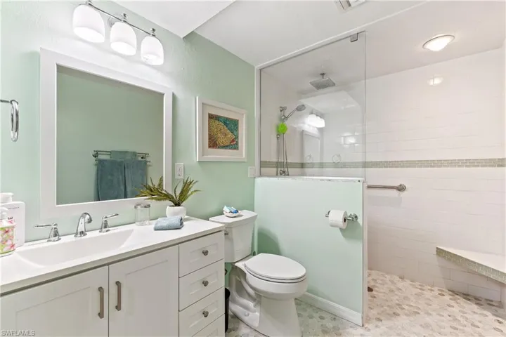 Bathroom featuring vanity, toilet, and a tile shower