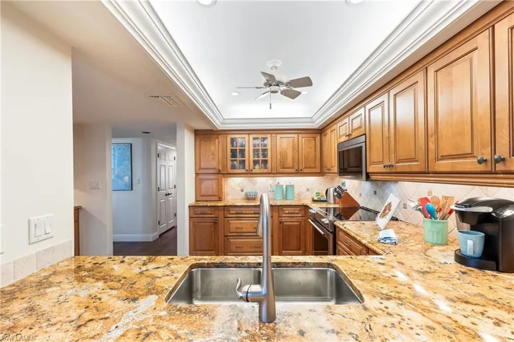 Kitchen with tasteful backsplash, light stone counters, high end stainless steel range oven, ceiling fan, and sink
