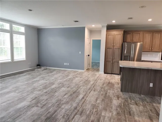 Kitchen with stainless steel fridge, light hardwood / wood-style floors, and crown molding