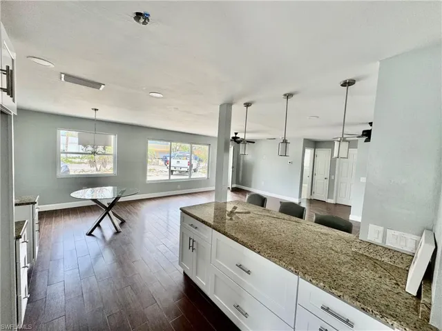 Kitchen with open floor plan, a ceiling fan, and light stone counters