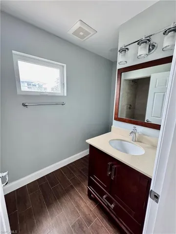 Full bathroom with vanity, visible vents, wood finished floors, walk in shower, and baseboards