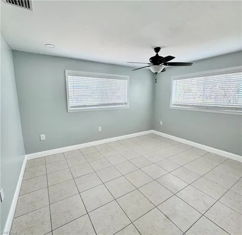 Spare room featuring visible vents, baseboards, a ceiling fan, and light tile patterned flooring