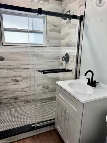 Full bath featuring wood finished floors, vanity, and a stall shower
