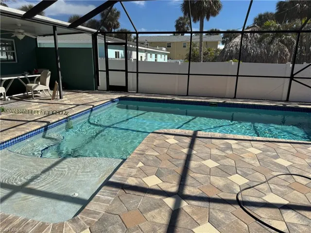 View of swimming pool featuring a patio, ceiling fan, and glass enclosure