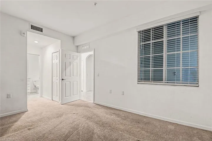Unfurnished bedroom with a closet, carpet floors, ensuite bathroom, and arched walkways