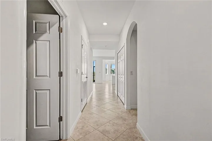 Hallway with arched walkways, light tile patterned floors, and recessed lighting