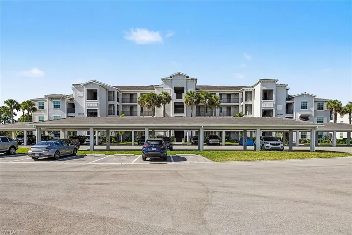 View of apartment building / complex featuring covered parking