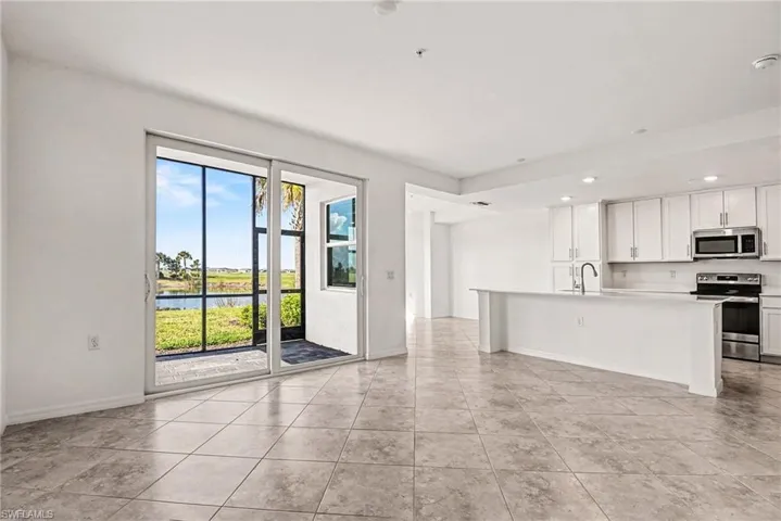 Kitchen featuring white cabinetry, appliances with stainless steel finishes, light countertops, a water view, and a kitchen island with sink