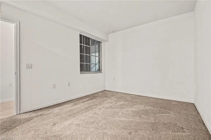 Empty room with light colored carpet and baseboards