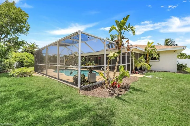 Back of house featuring glass enclosure and a lawn