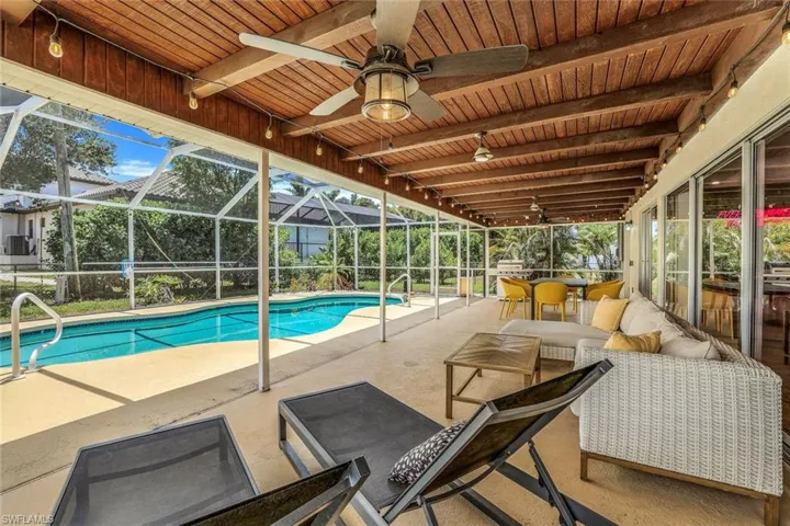 View of pool with outdoor lounge area, glass enclosure, a patio area, and ceiling fan