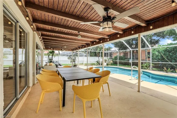 View of pool with a patio, glass enclosure, and ceiling fan