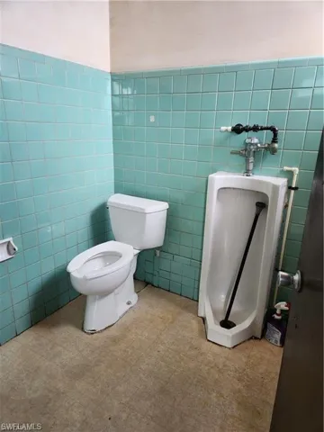 Bathroom with toilet and tile walls