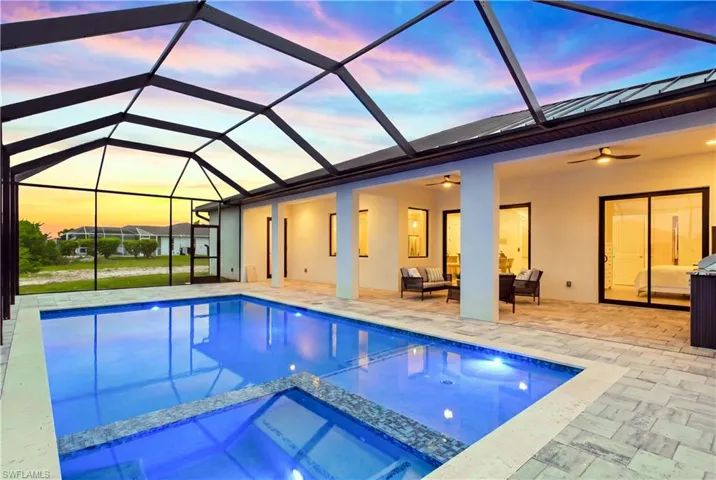 Screened-in swimming pool and spa with integrated lighting, a paver patio, and covered lanai with multiple sets of sliding glass doors