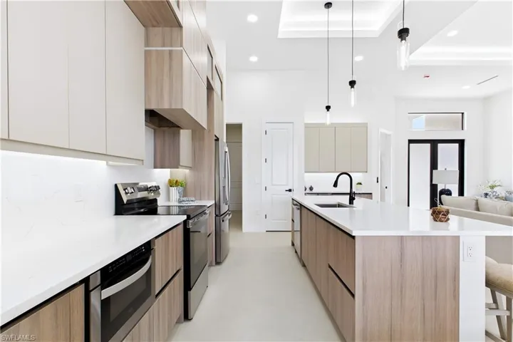 Modern kitchen featuring white countertops, stainless steel appliances, wood-finish cabinetry, a kitchen island with seating, and recessed lighting