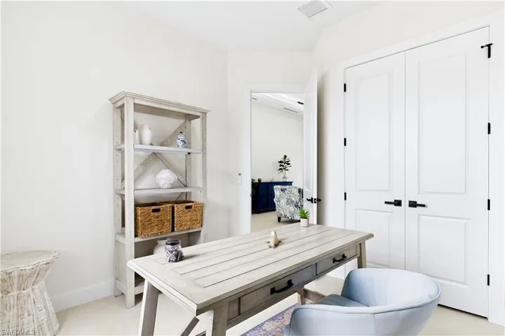 White painted walls, double panel doors with matte black hardware, and an open doorway to another room