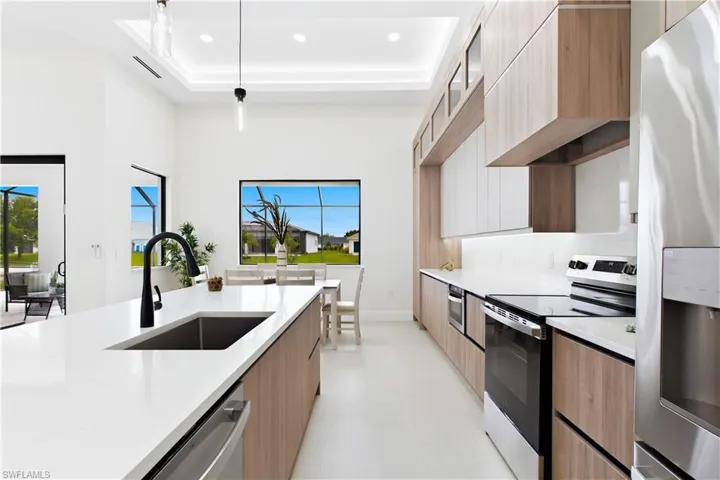 Spacious kitchen featuring an expansive island with an undermount sink, stainless steel appliances, and wood-finish cabinetry