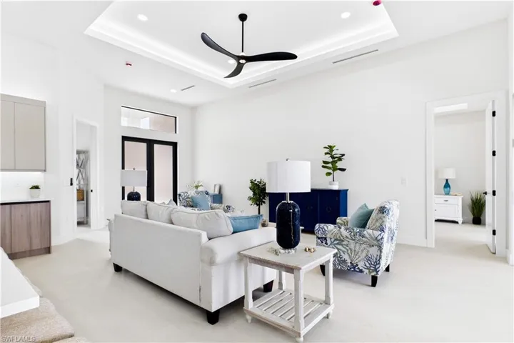 Recessed lighting, tray ceiling, ceiling fan, neutral flooring, and contemporary cabinetry