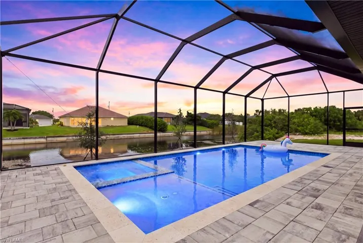 Screened-in outdoor living space with a rectangular pool, integrated spa, and pavers