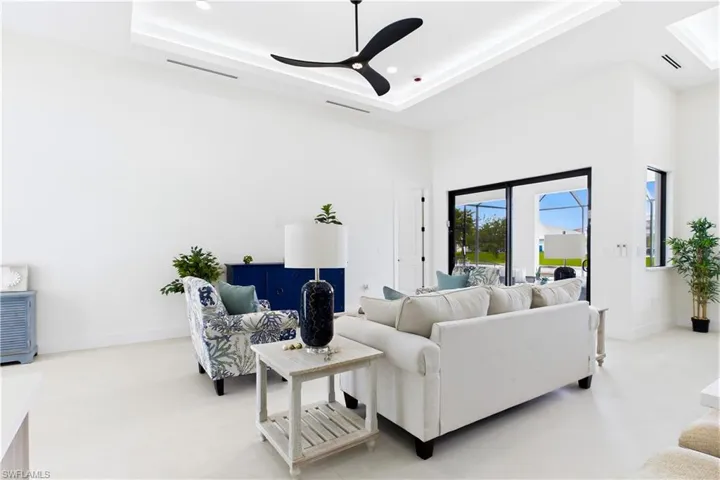 High ceilings with recessed lighting, black ceiling fan, large sliding glass doors, white walls, and light-colored flooring