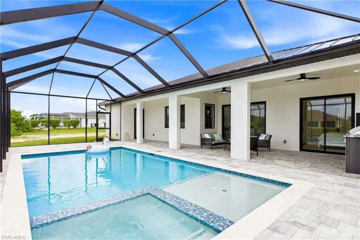 Screened lanai featuring a swimming pool, integrated spa, and an expansive paved deck
