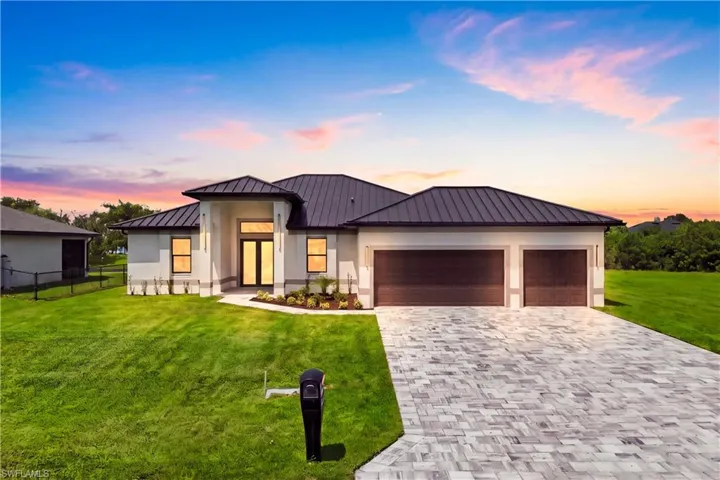 Contemporary exterior with a metal roof, a paver driveway, and a two-car garage