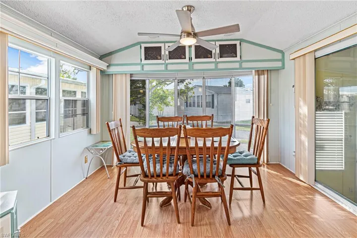 Dining area with a textured ceiling, lofted ceiling, and a ceiling fan