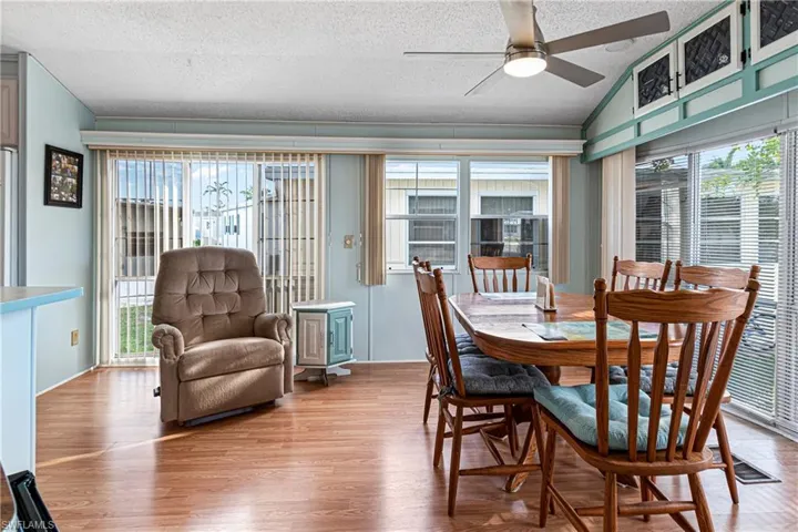 Dining room featuring a textured ceiling, wood finished floors, lofted ceiling, and a ceiling fan