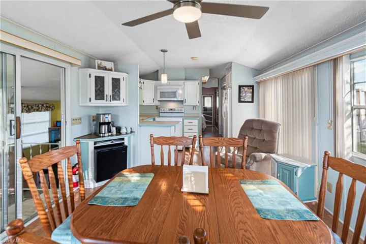 Kitchen with vaulted ceiling, white appliances, pendant lighting, light countertops, and light wood-type flooring