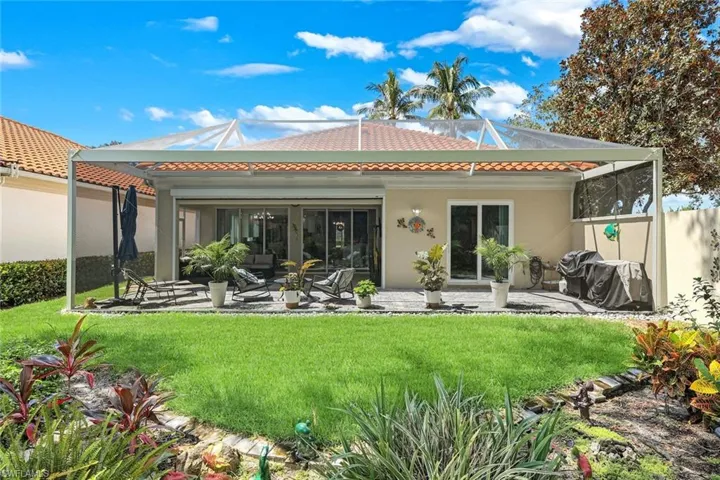 Screened patio enclosure with a tiled roofline, sliding glass doors, and a paver patio
