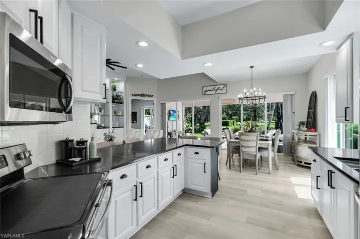 Spacious kitchen featuring white cabinetry, dark countertops, a stainless steel microwave, and wood-finish flooring