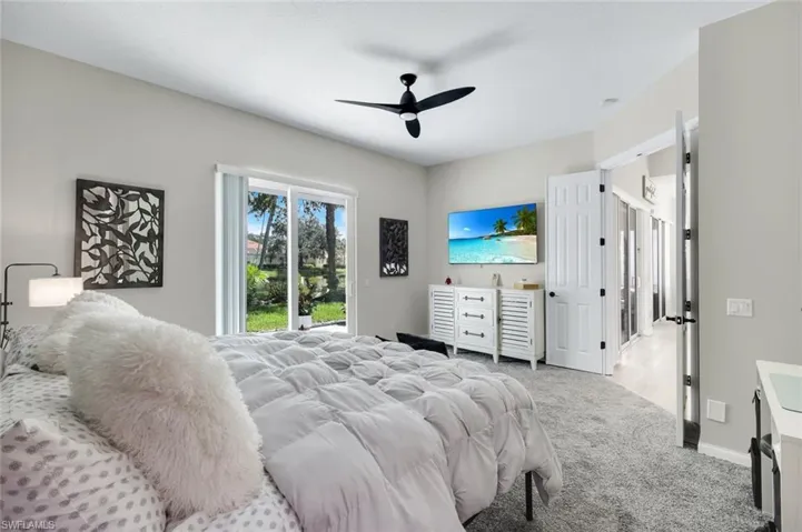 Sliding glass doors opening to outdoor space, ceiling fan, neutral wall tones, and carpeted flooring