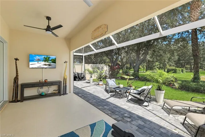 Screened lanai featuring a ceiling fan, a wall-mounted television, and a paver patio