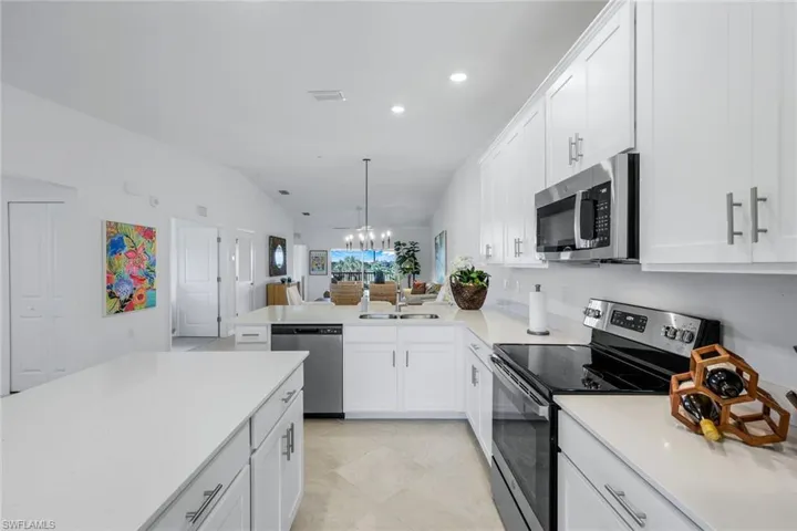 Kitchen with appliances with stainless steel finishes, white cabinets, recessed lighting, a peninsula, and hanging light fixtures